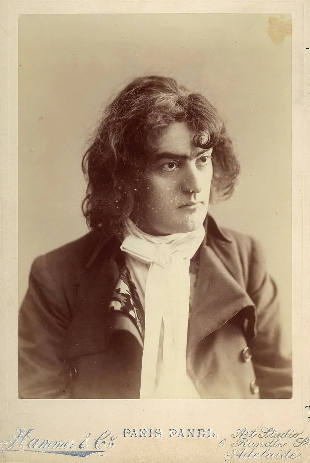 A studio photograph from about 1900 of the actor Tyrone Power senior in costume as Sidney Carton, in a long coat with a high collar