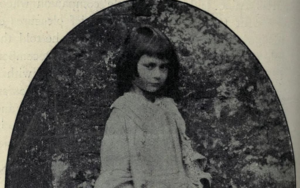 A circa-1858 photograph by Lewis Carroll of young Alice Liddell, the real girl behind the book, standing in a garden in an oval vignette