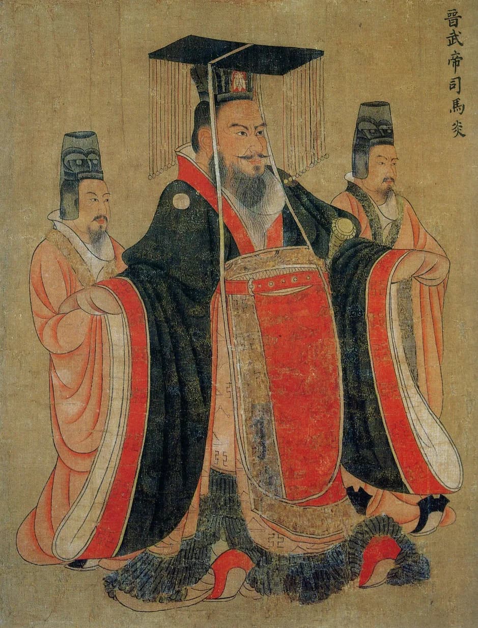A detail of an ancient Chinese handscroll showing a bearded emperor in a black and red robe and tall crown, flanked by two smaller attendants, with a vertical inscription naming him