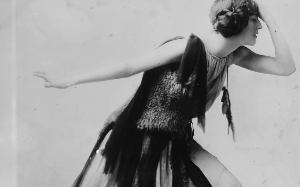 Violet Romer photographed in a flapper dress by the Bain News Service, mid-dance with one arm extended